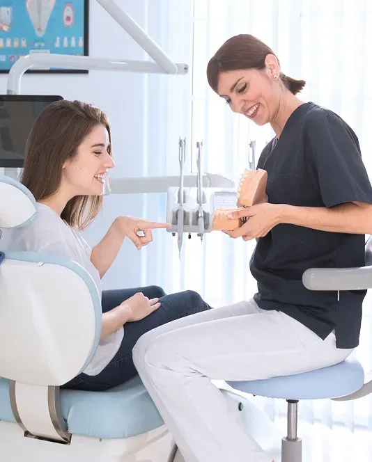 Friendly dental professional discussing treatment options with a smiling patient in a modern dental clinic.