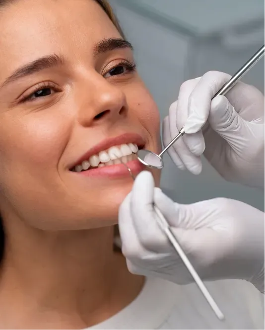 Close-up of a smiling patient receiving a dental examination with a dental mirror and professional instruments.