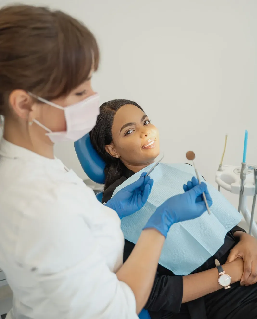 Dental professional providing treatment to a relaxed patient seated comfortably in a dental chair.