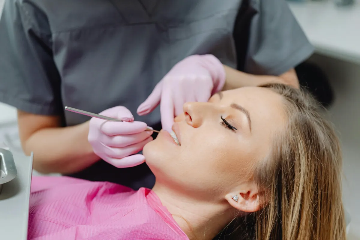 Patient receiving a gentle dental examination while a dental professional uses a mirror to assess their teeth.