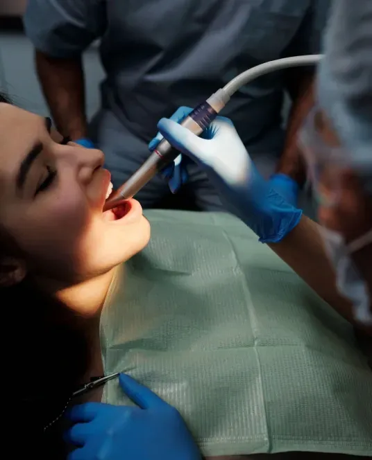 Patient receiving professional dental treatment using specialised dental equipment in a clinical setting.