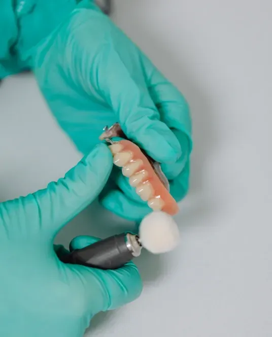 Dental professional polishing and finishing a custom dental bridge restoration.
