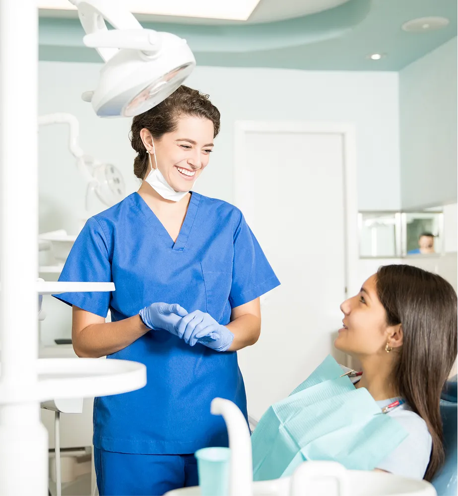 Friendly dental professional speaking with a smiling patient before treatment in a modern dental clinic.