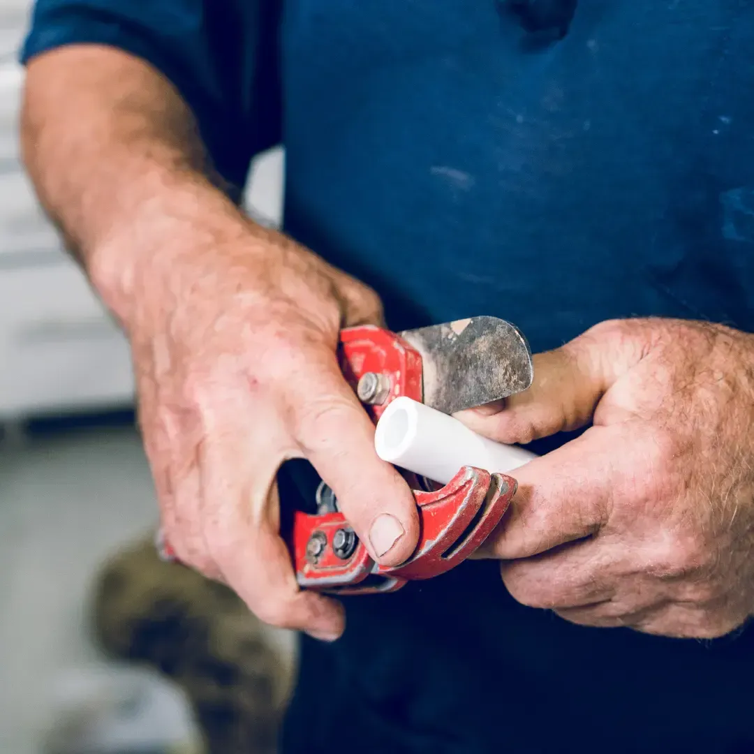 Plumber using pipe cutter during residential plumbing maintenance and preventive service by MMI Home Manager