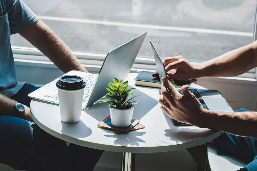 two people sitting a table with laptops