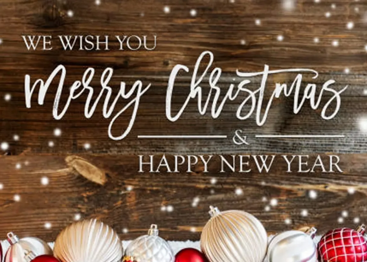 “Merry Christmas and Happy New Year” greeting with ornaments and wooden background.