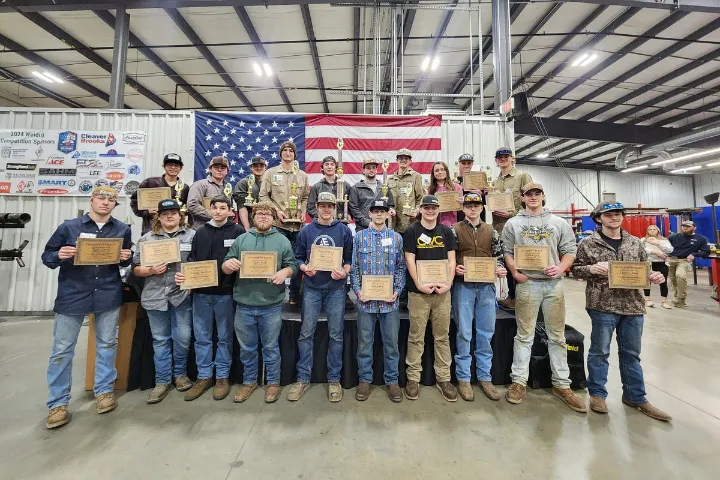 Group of students learning welding in a workshop.