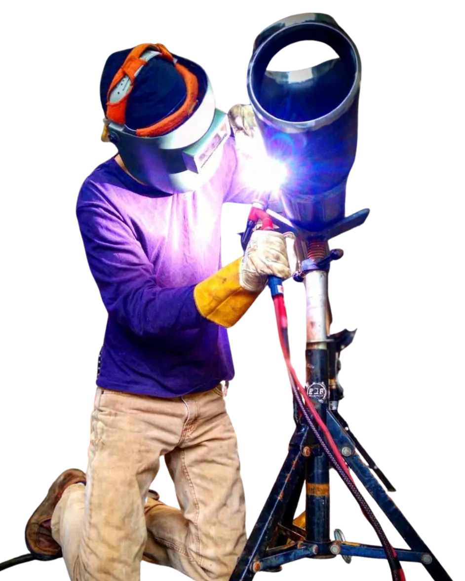 Smiling welder in blue uniform lifting his helmet while holding a welding rod.