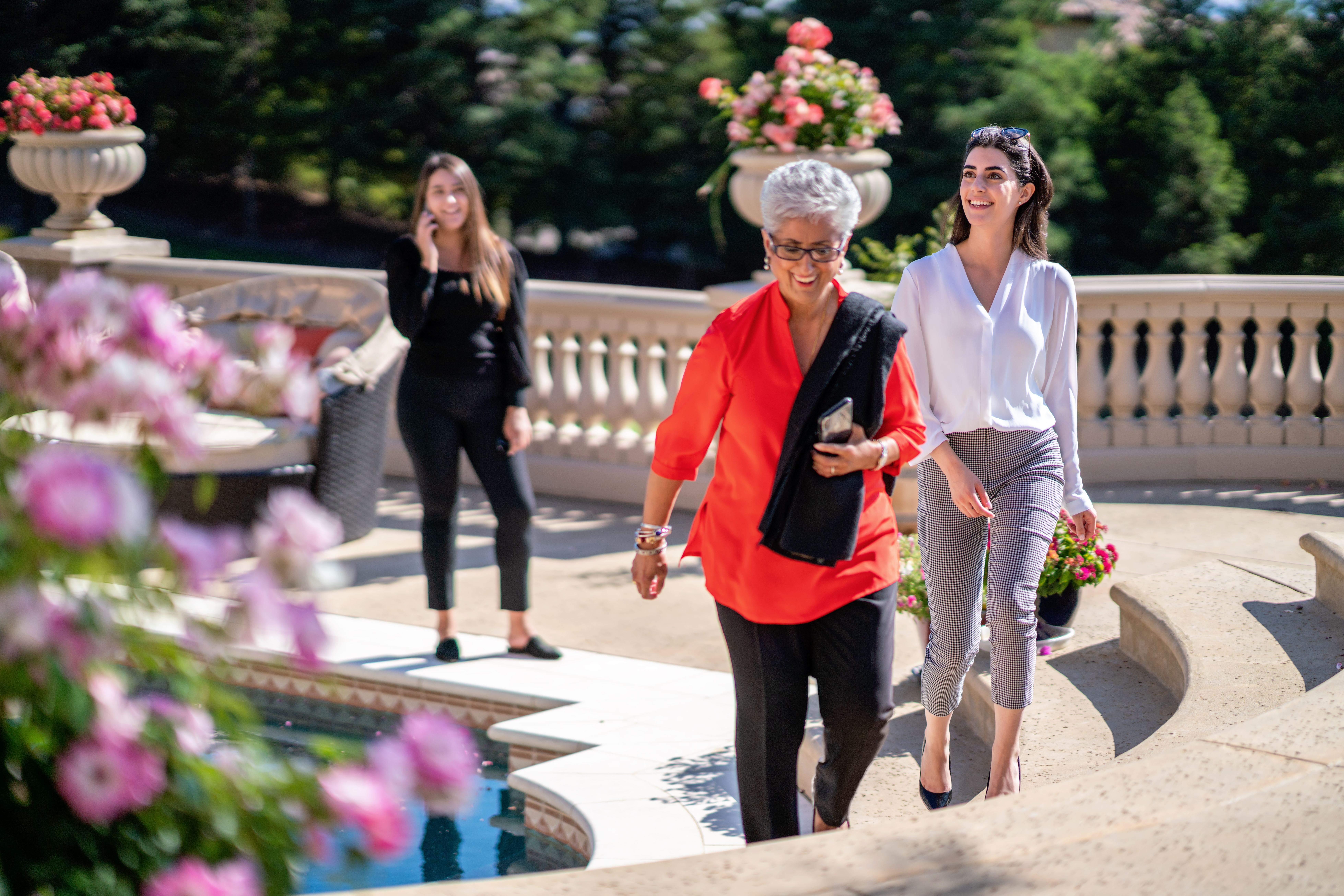Women walking on luxury outdoor patio with pool and garden, elegant lifestyle and social moment