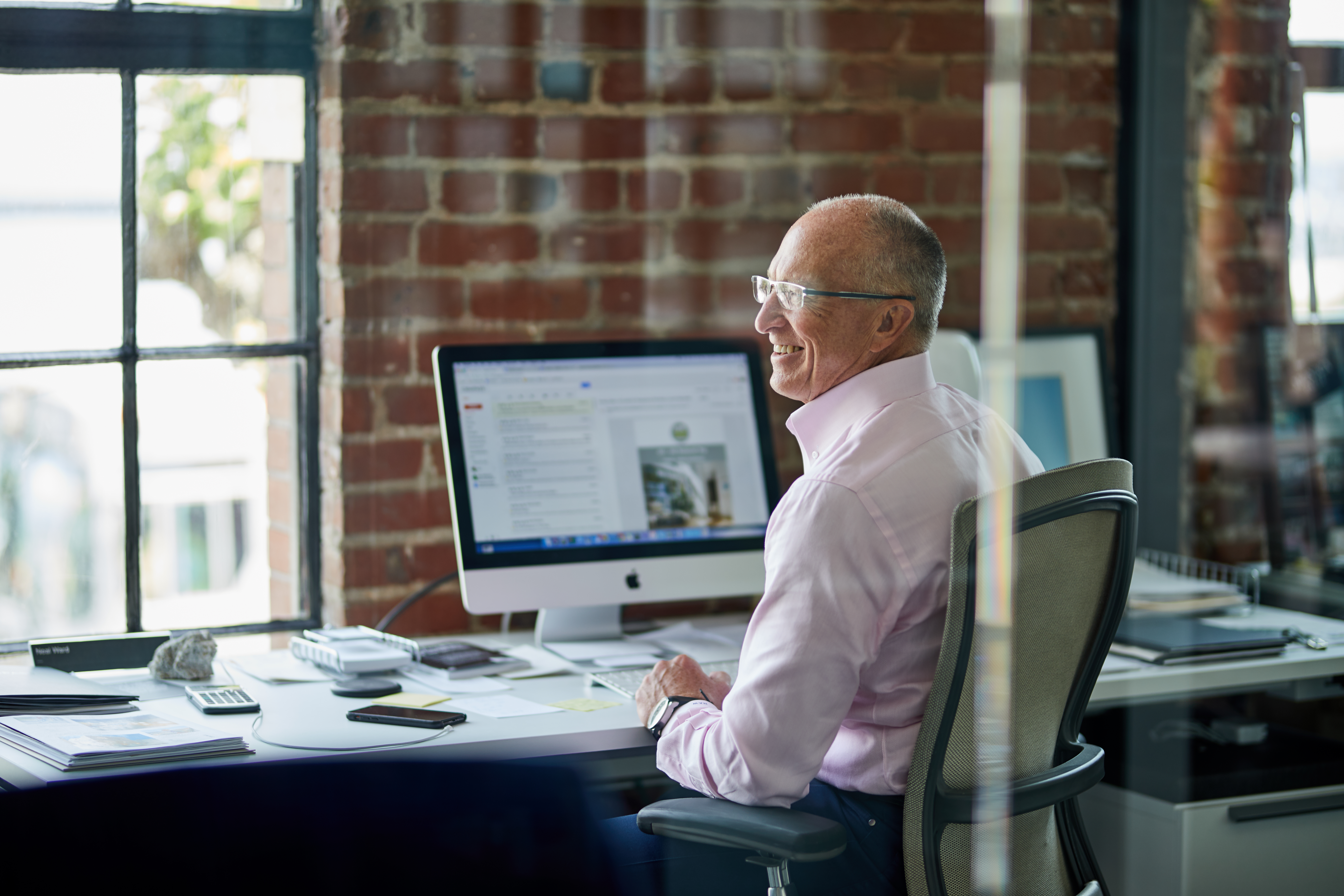 man working in office behind glass door laughing and looking to the side realtor agent portrait