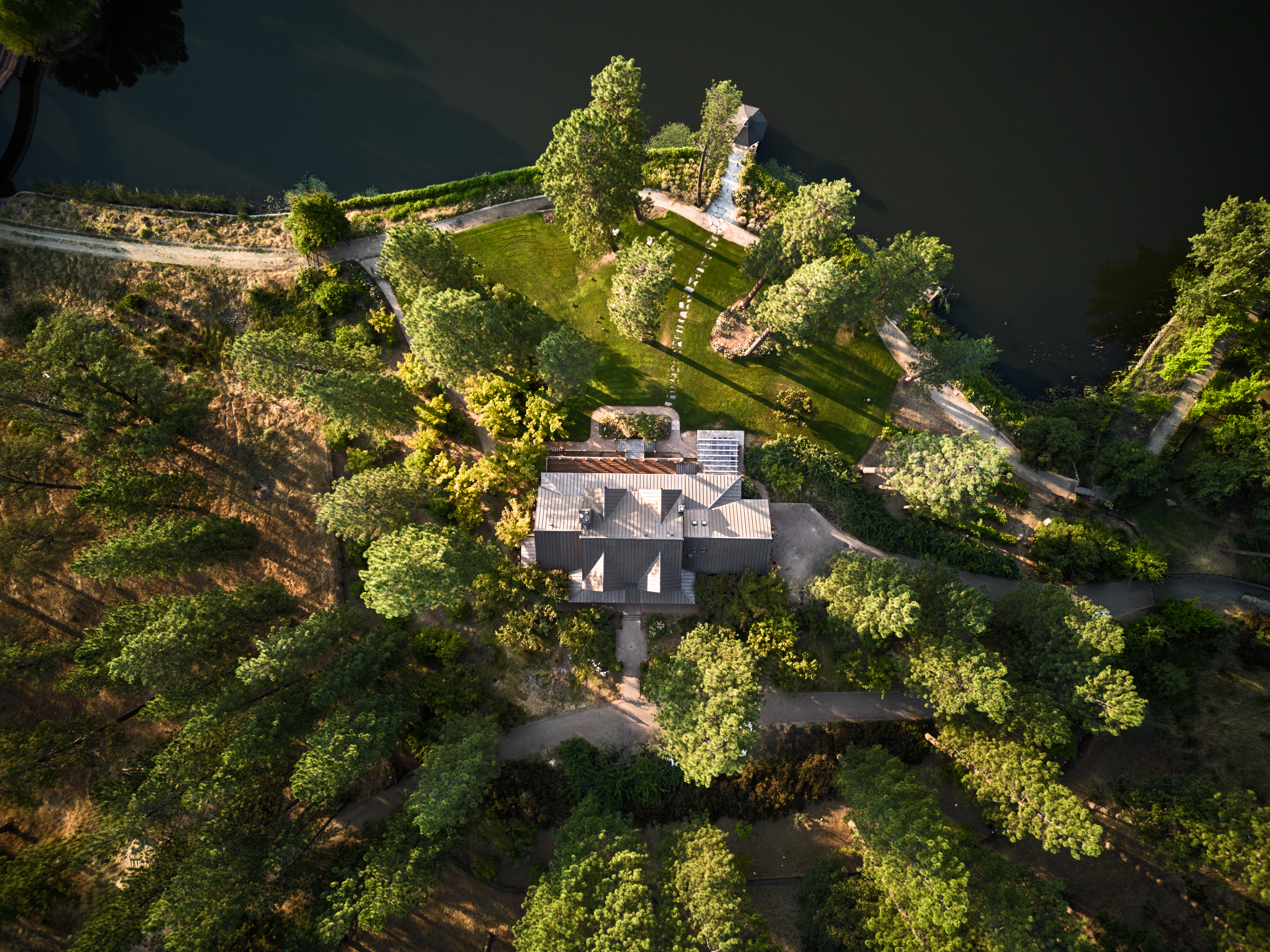 over head shot of a house in the woods by a lake. drone photography