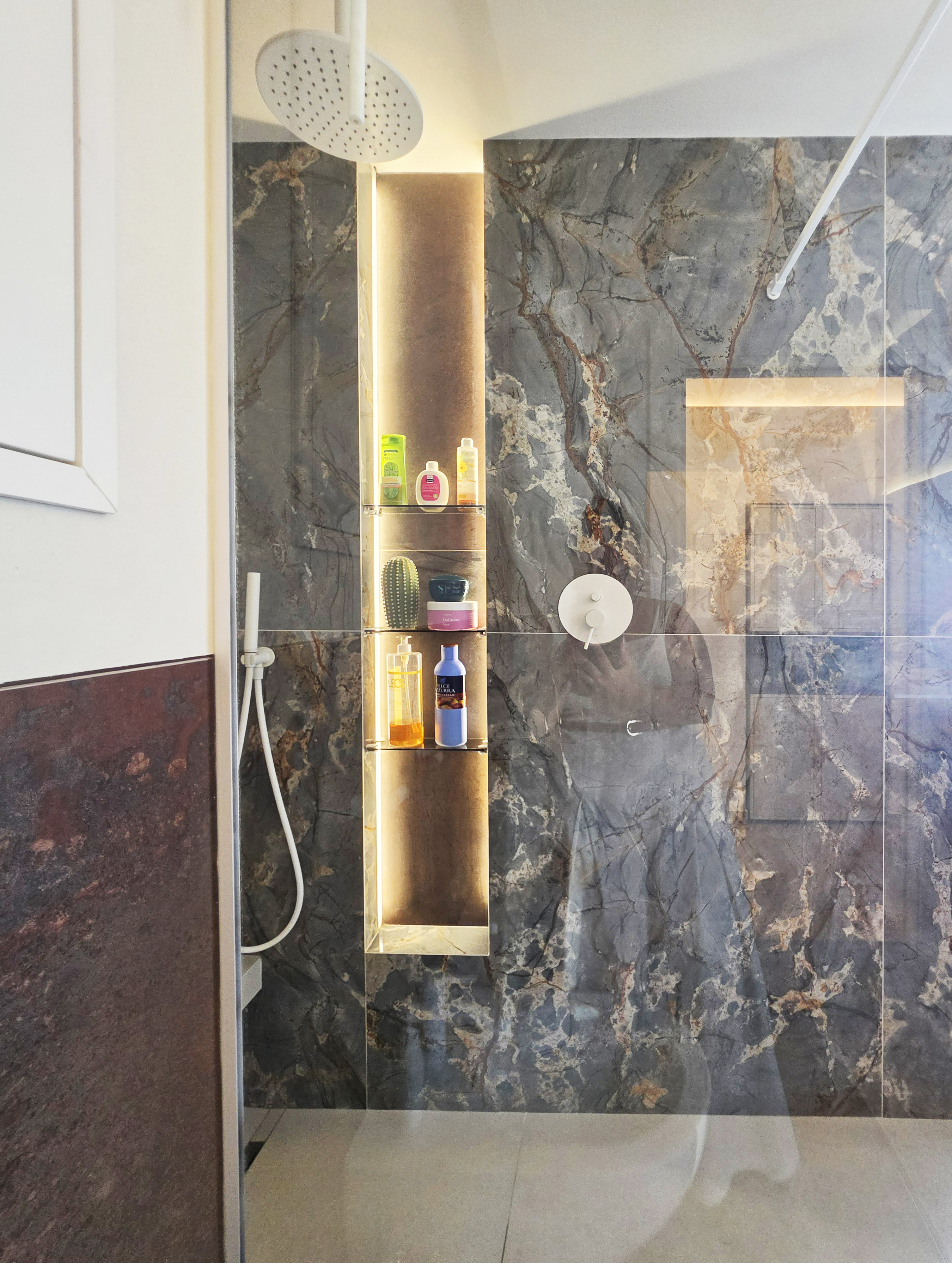 Bagno con rivestimenti minerali scuri e nicchie illuminate
