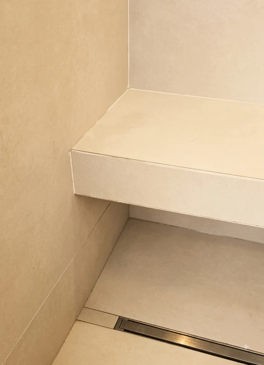 Bagno con superfici continue color arena e sedute integrate