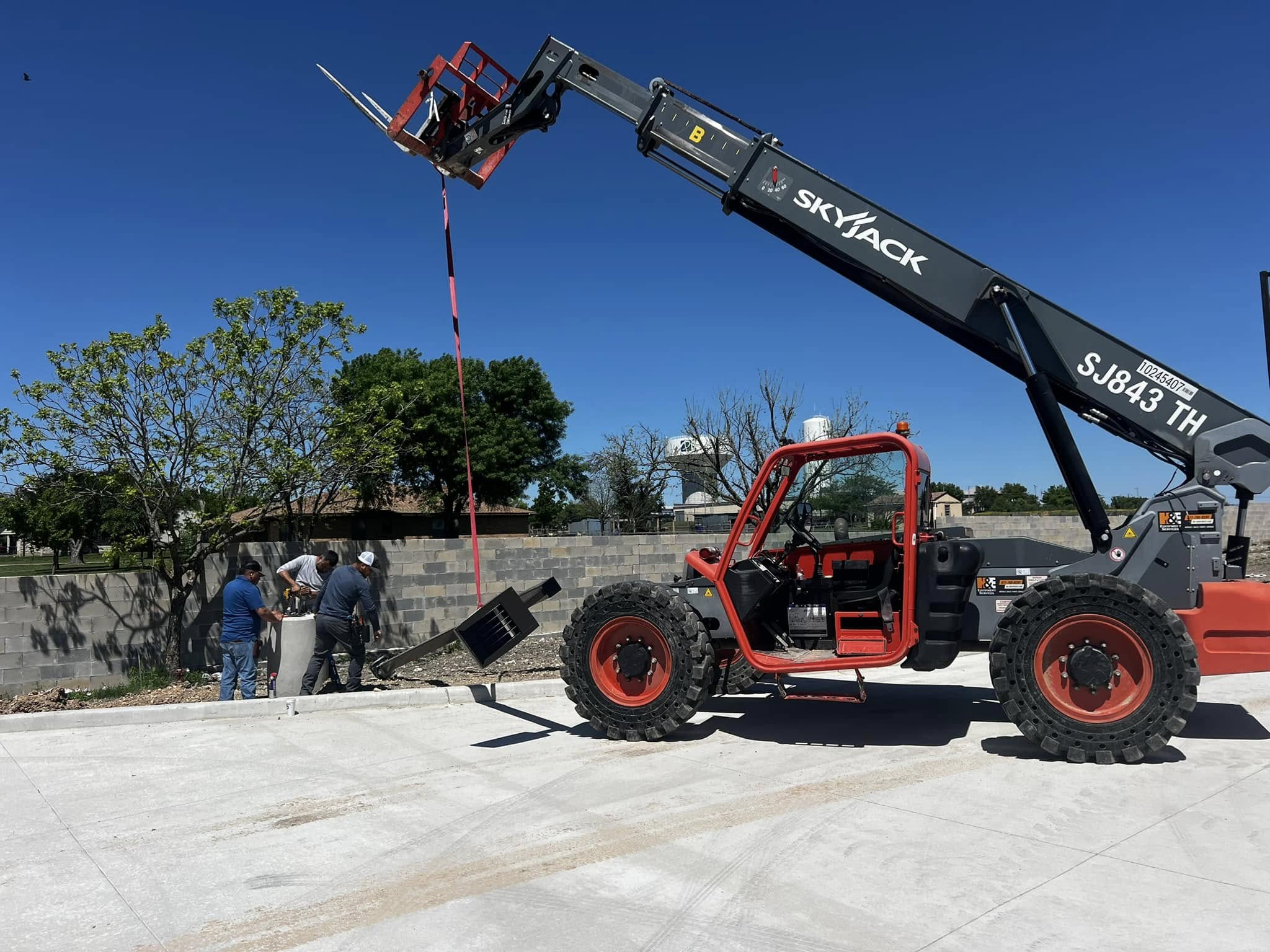 Skyjack telehandler and crew setting up electrical equipment at new commercial construction site, Texas
