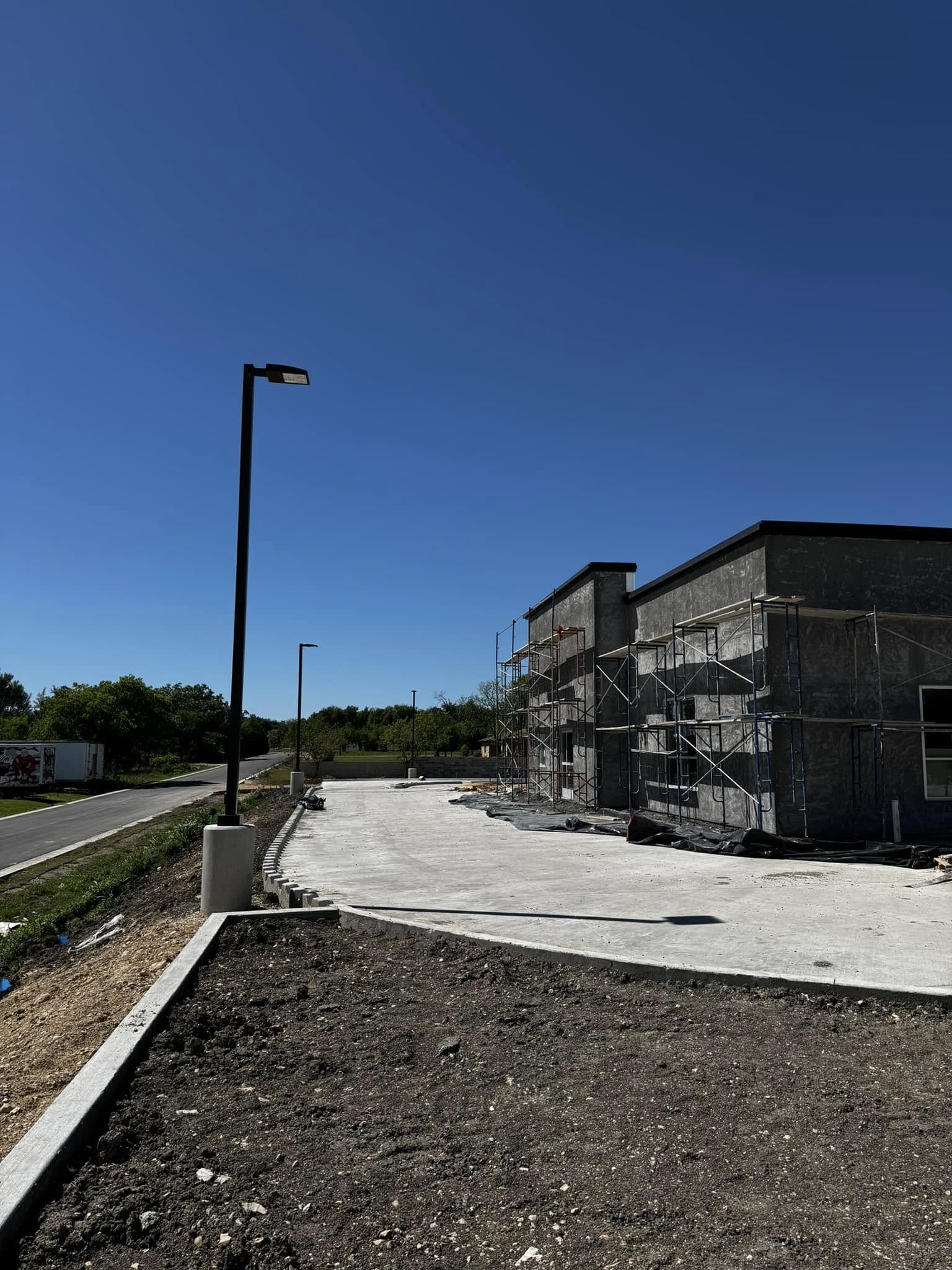 New commercial building under construction with installed parking lot light poles, Central Texas