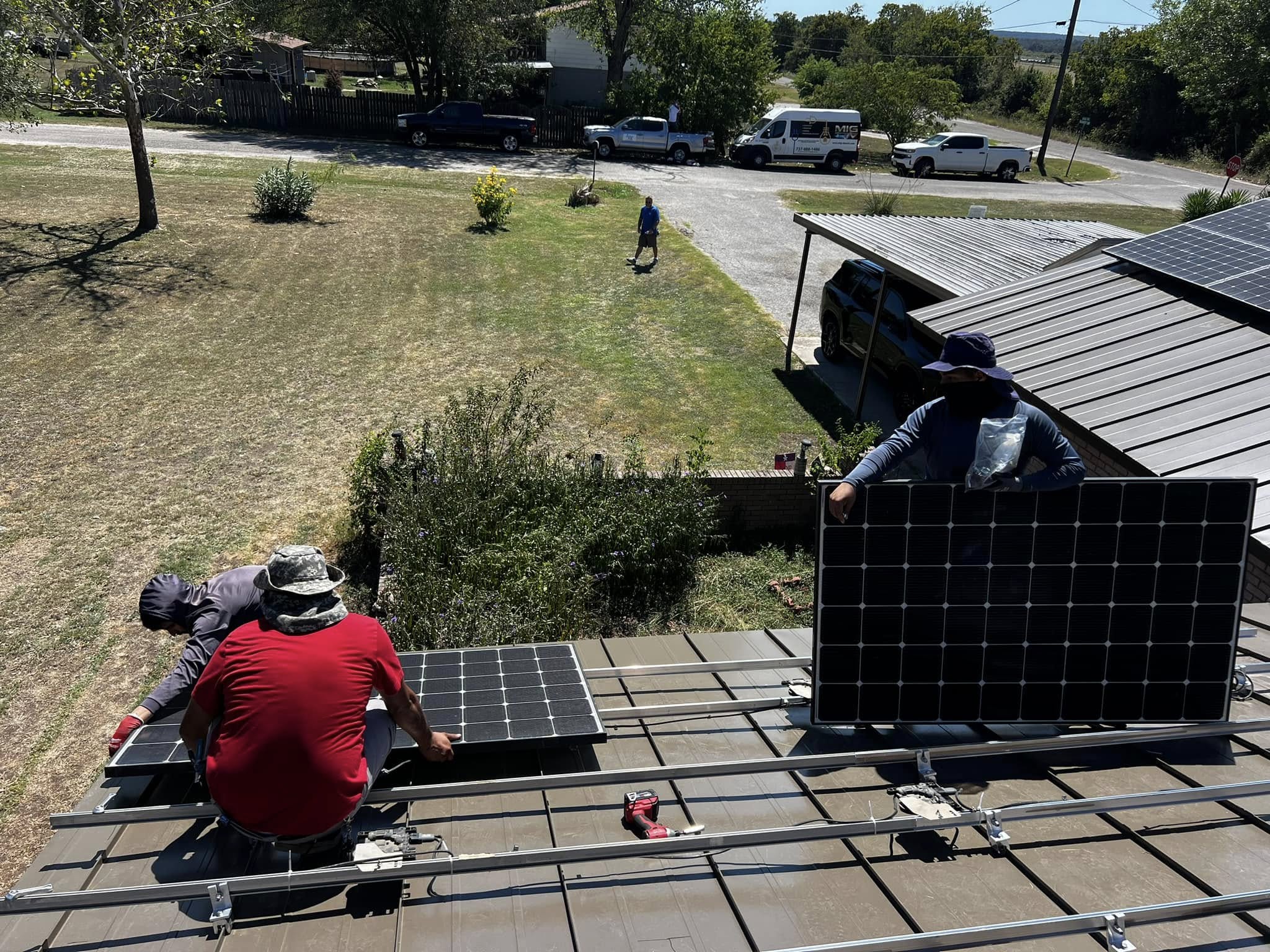 Electricians placing solar panels on residential rooftop, Central Texas