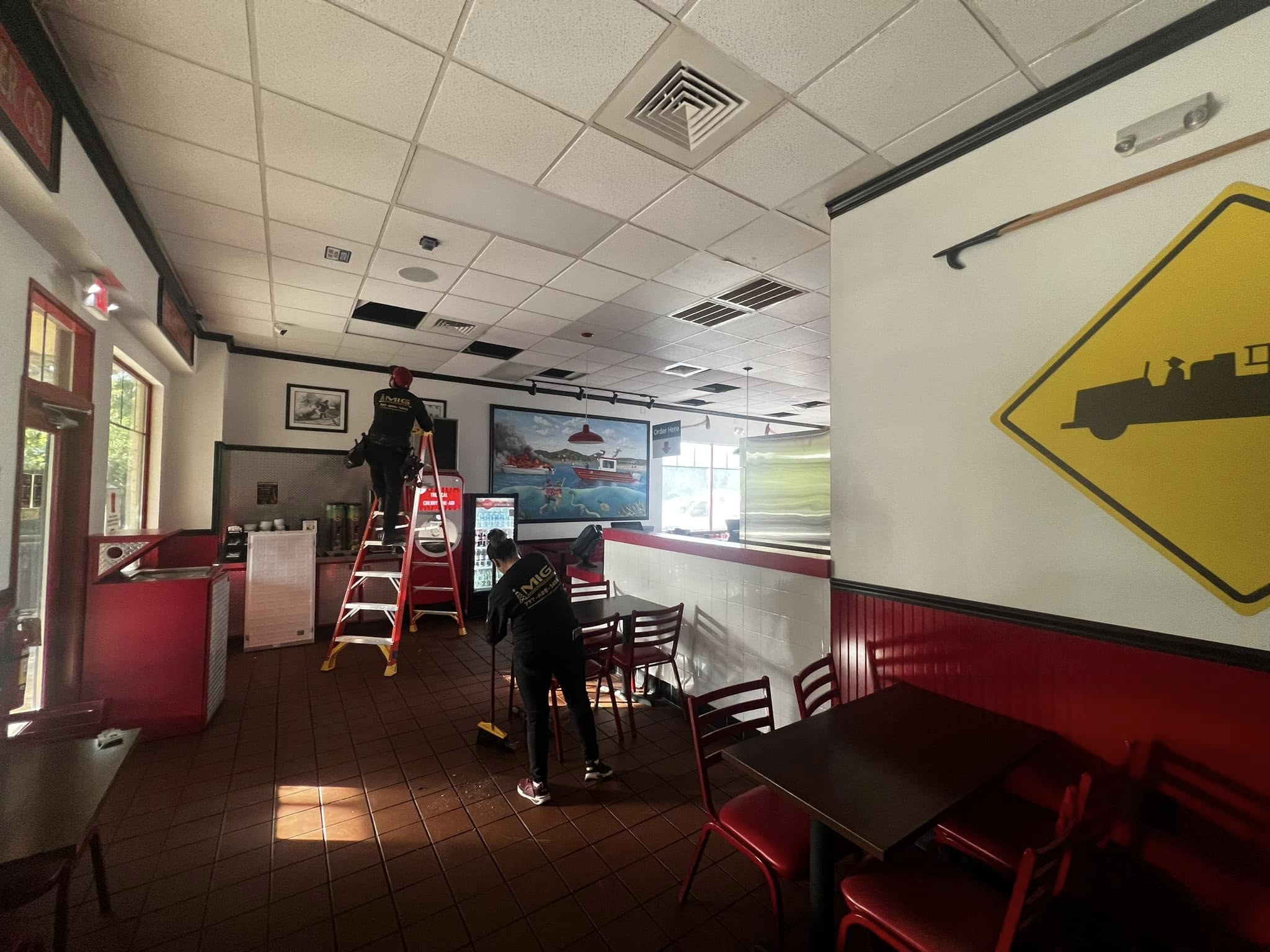 Electricians performing ceiling electrical work inside commercial restaurant, Austin TX