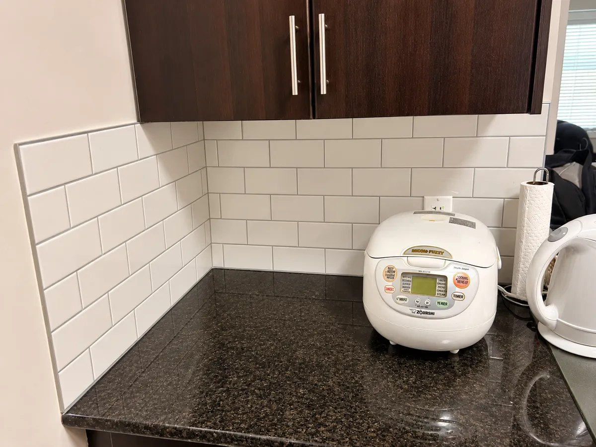 Subway tile backsplash installation with dark kitchen cabinets in Calgary