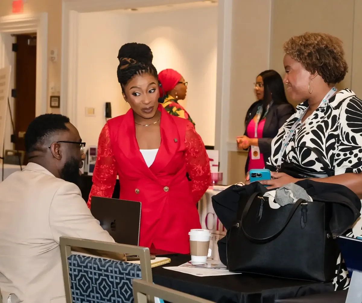 Dr. Ogo in a red blazer advising attendees at a workshop table