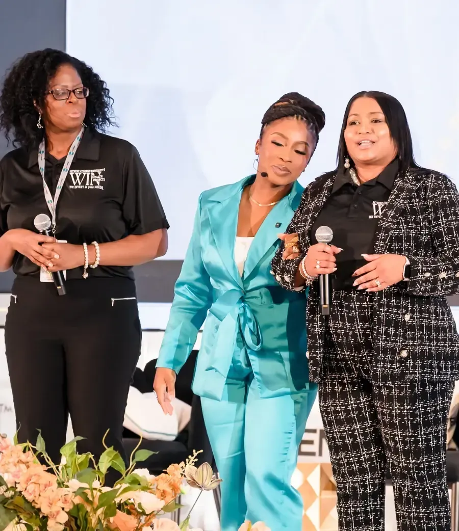 Dr. Ogo in a teal suit on stage with two Career Haven event attendees