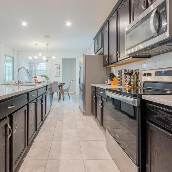 Large galley kitchen with island, stainless steel appliances, granite countertops, spice rack, and knife block with dining area in background