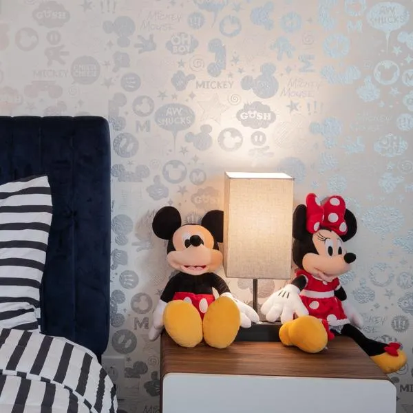 Mickey and Minnie Mouse plush toys sit on a nightstand in Mickey Mouse themed bedroom.