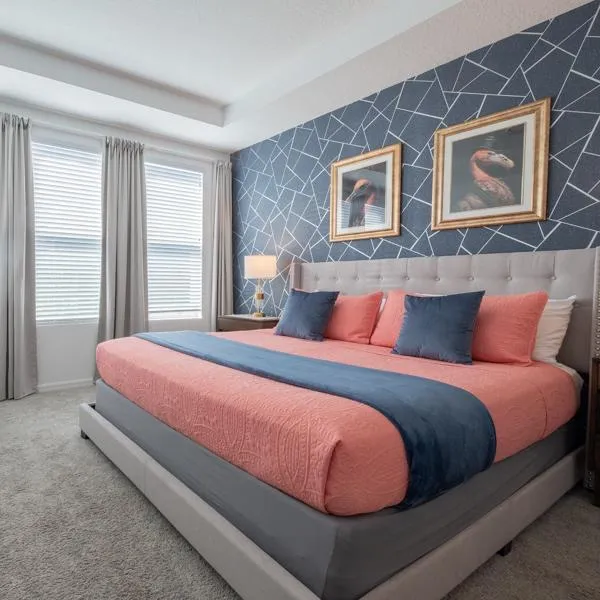 Flamingo themed master Suite bedroom with king sized bed, high tray ceiling, dark blue wallpaper, flamingo portraits, USB charging bedside lamps, and coral bedding