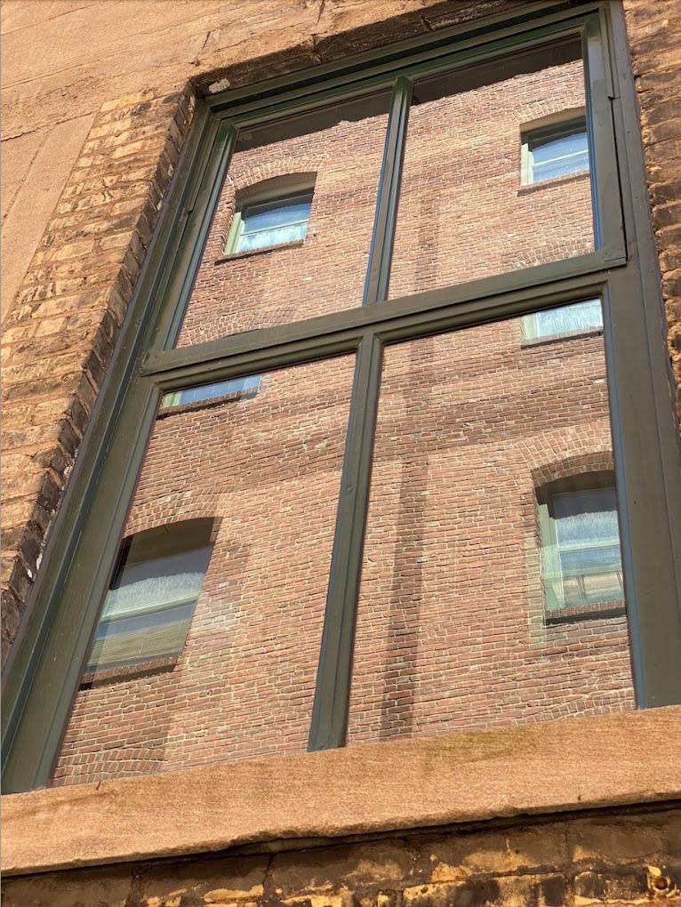 Clean commercial building windows with dark frames on brick facade after professional window washing