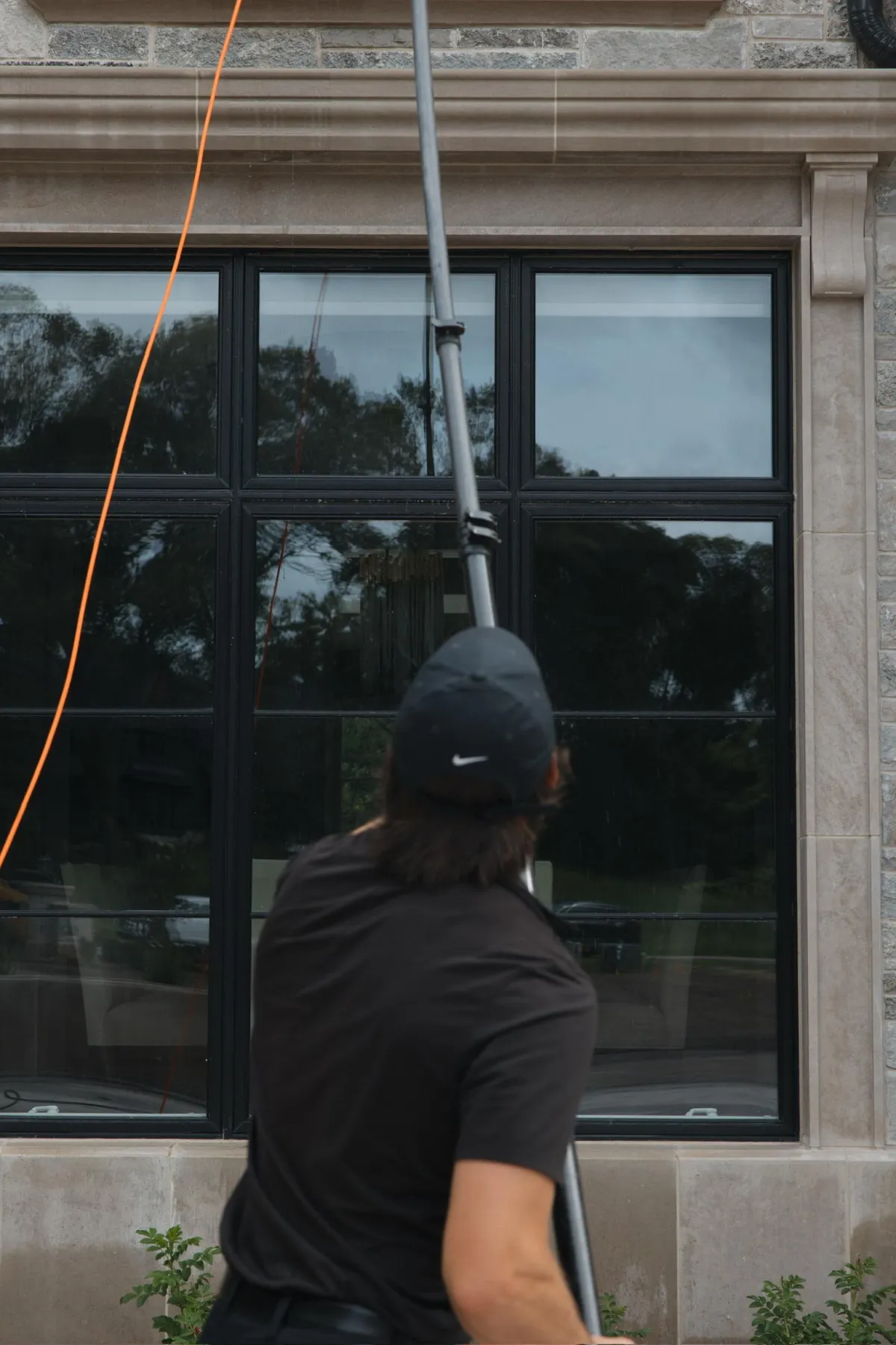 Window cleaning technician washing large commercial windows with professional squeegee equipment