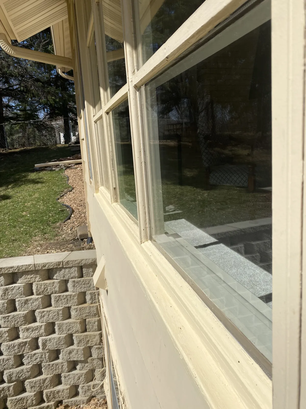Clean residential windows with white frames on stone foundation after professional window washing
