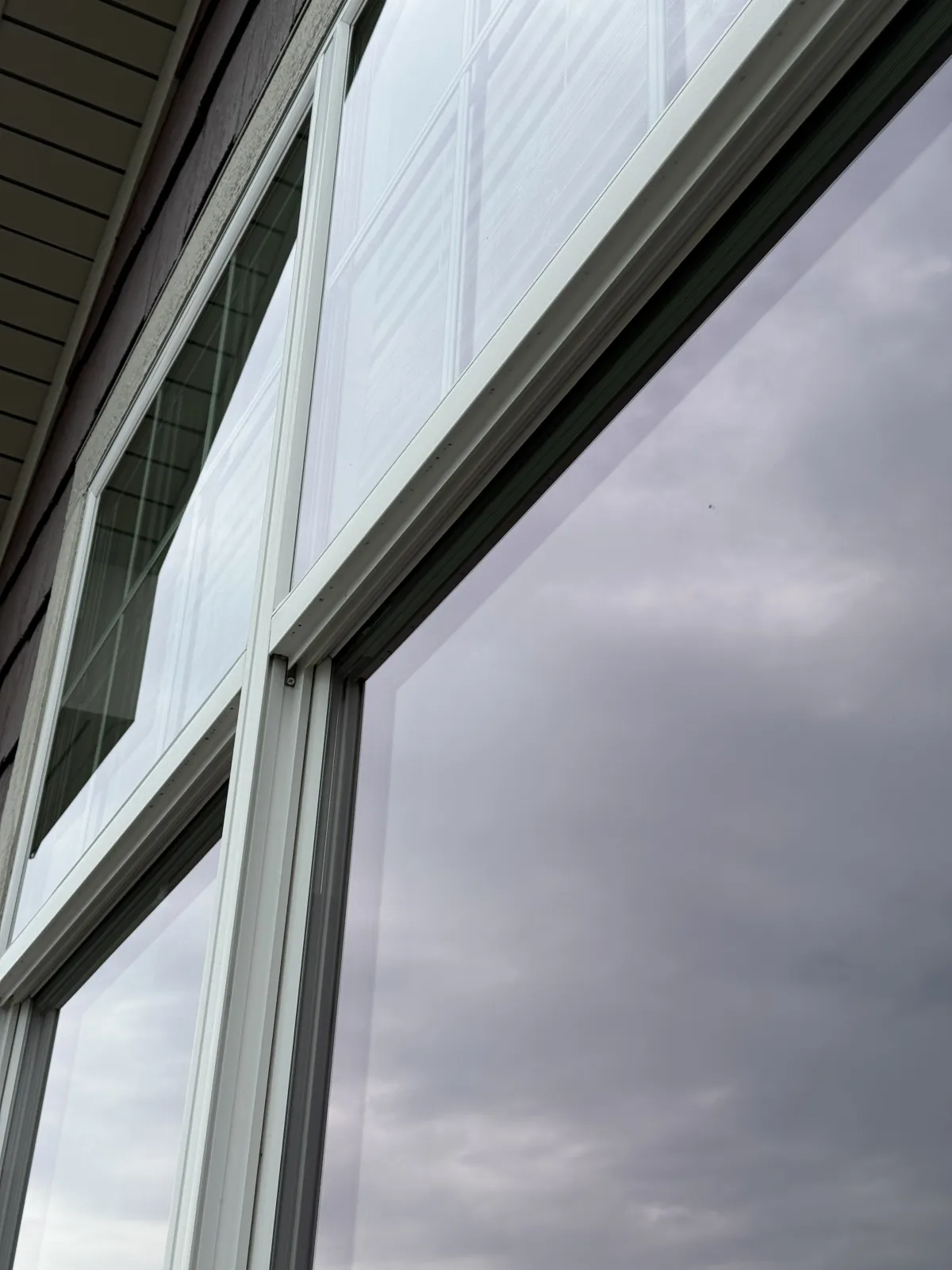 Clean residential windows with dark frames reflecting clear sky after professional window cleaning service