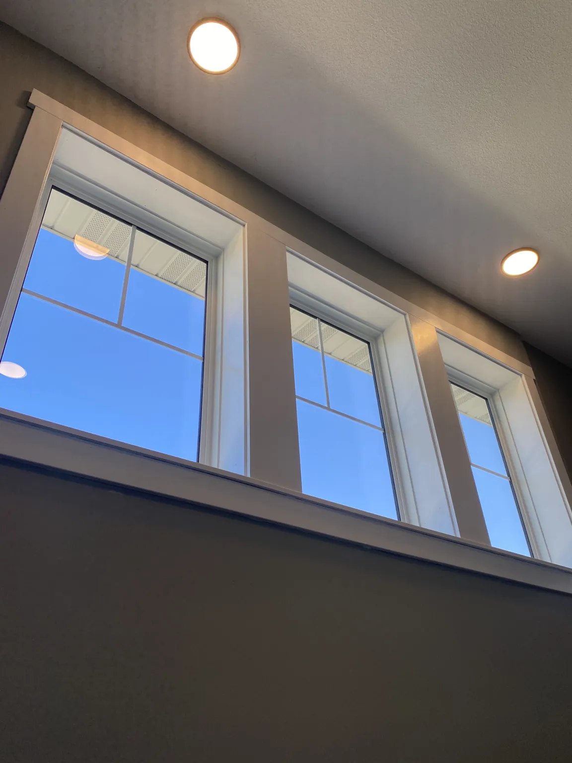 Spotless interior view of three windows with white trim showing blue sky through crystal clear glass