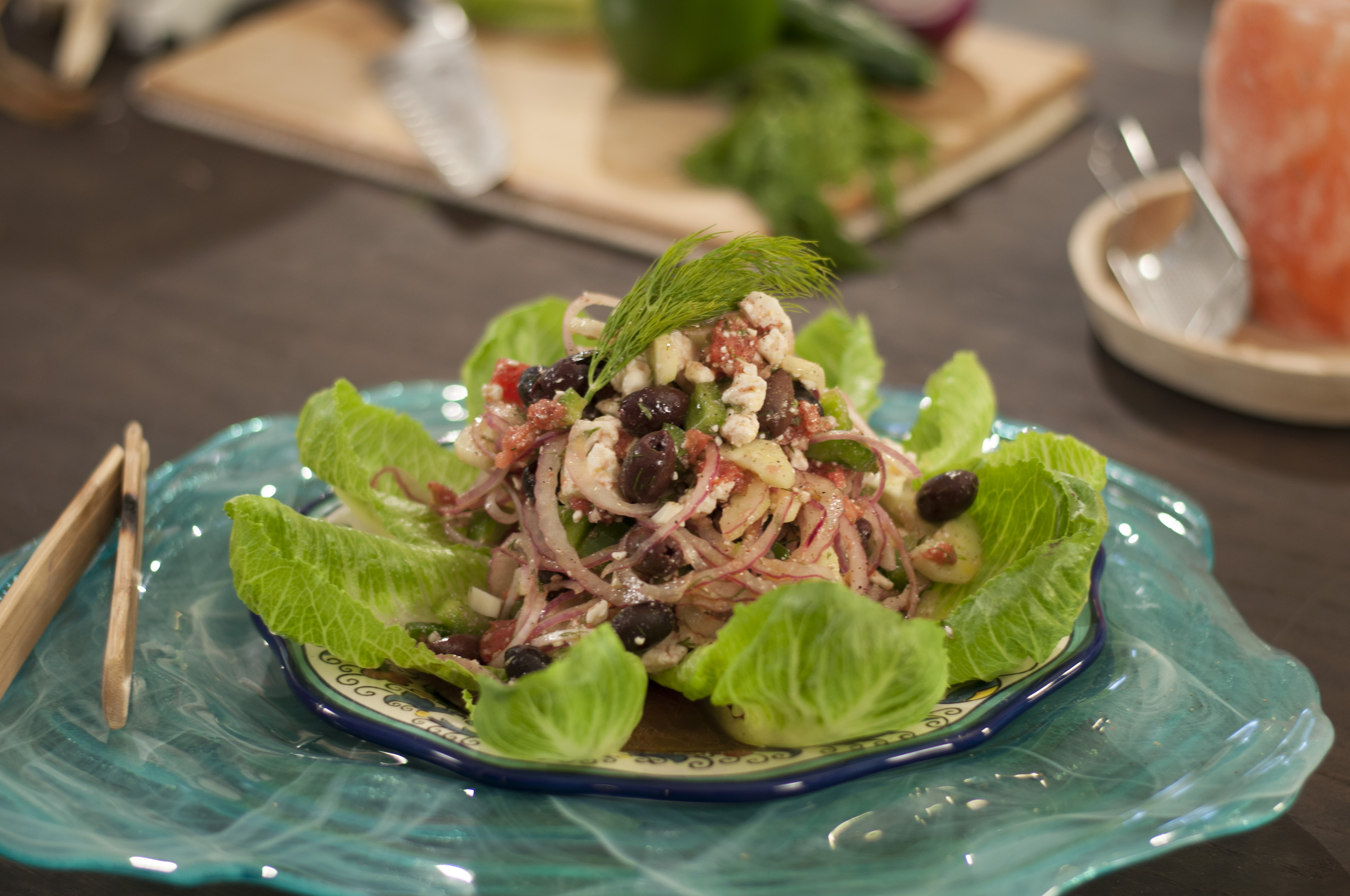 A Greek salad is featured on romaine leaves.