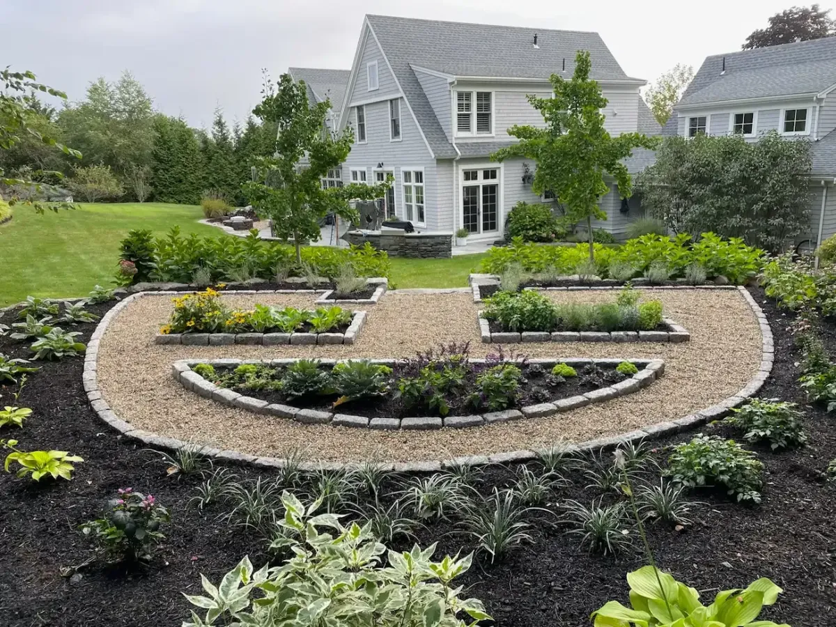 Custom formal garden with raised planting beds, gravel walkways, lush landscaping, and residential landscape design in Marblehead, MA