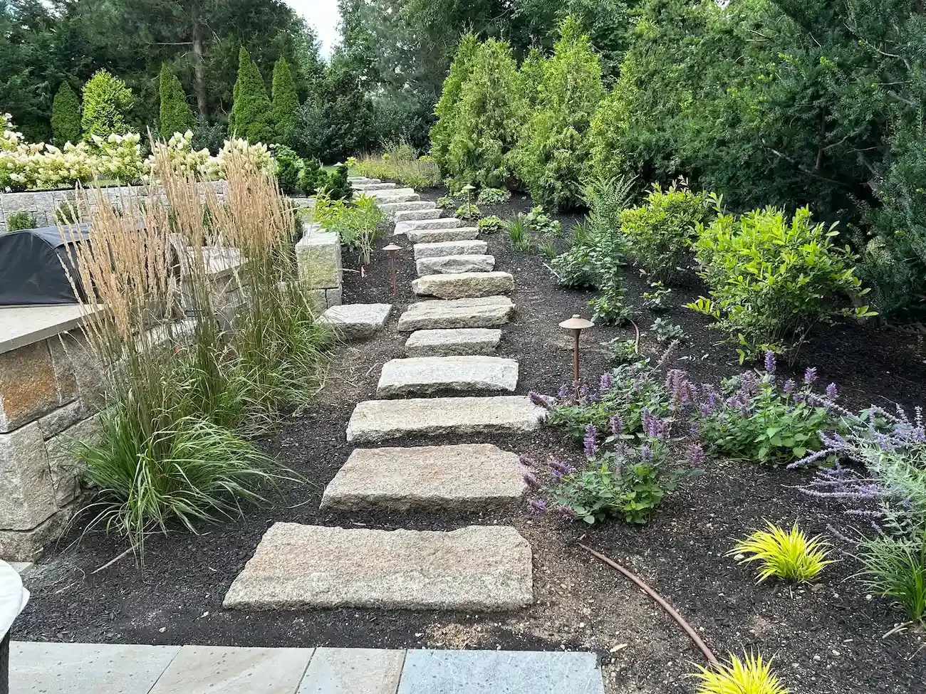 Natural stone garden steps with flowering perennials, ornamental grasses, shrubs, and custom landscape design in Marblehead, MA