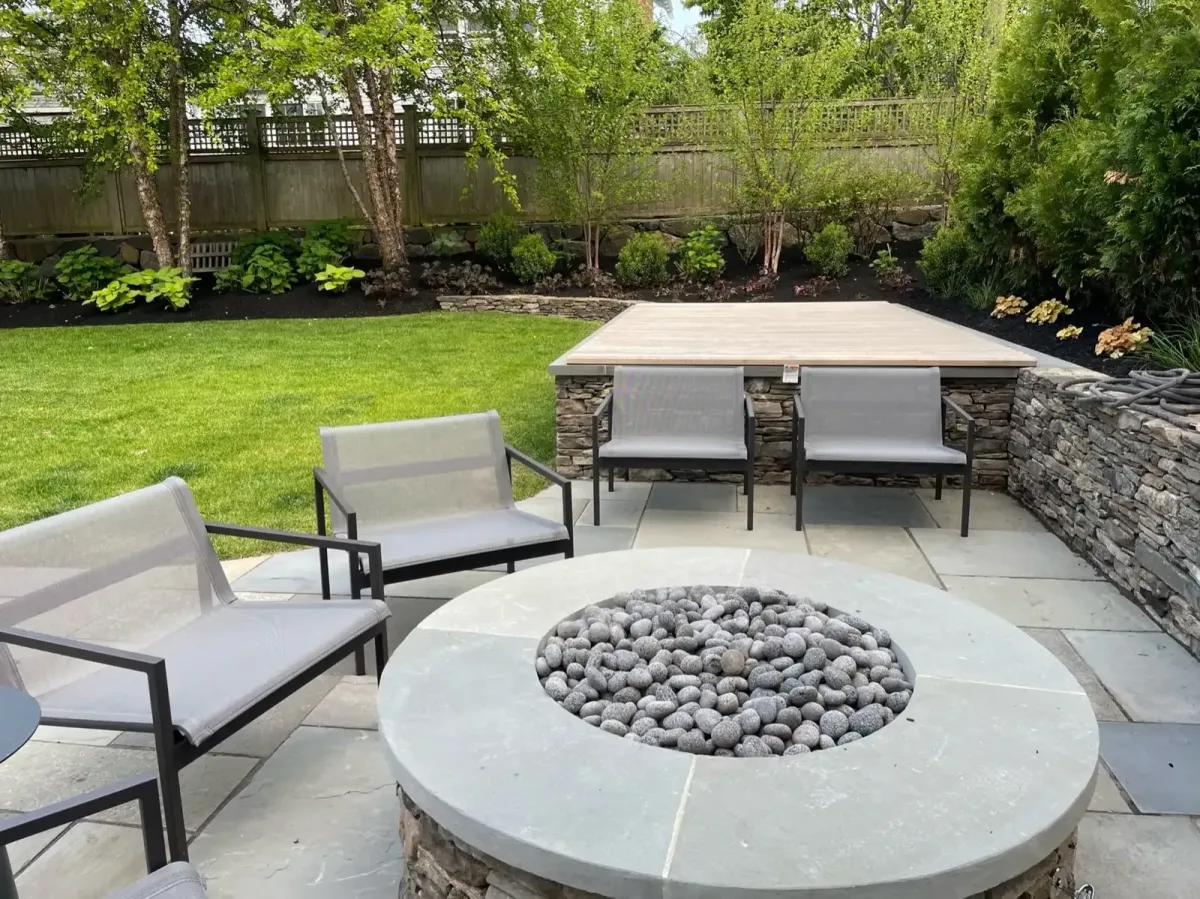 Custom stone fire pit patio with seating and landscaped backyard in Marblehead, MA