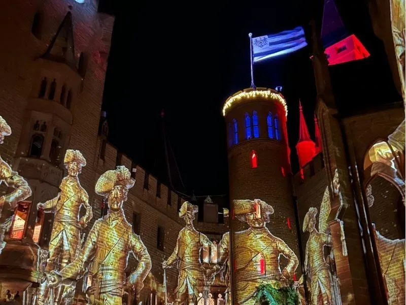 Light show projected onto the walls of Burg Hohenzollern during a royal Christmas market in the castle courtyard