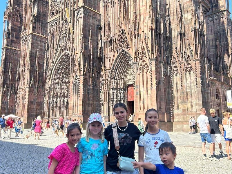 Kids and teens standing in front of the Strasourg cathedral in France during a group Europe trip 