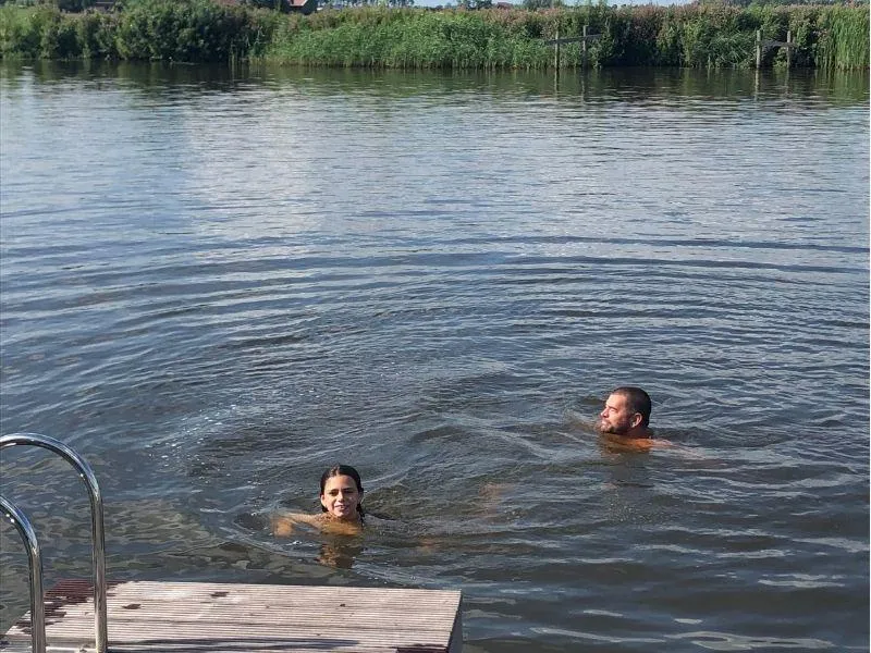 Parent and child swimming together in a peaceful river in the Netherlands during a summer Europe trip