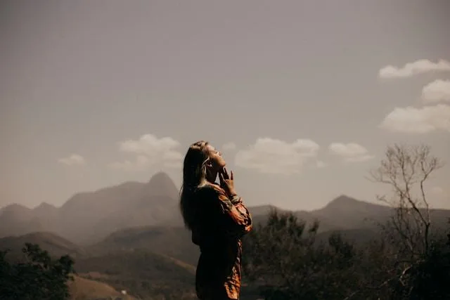 Vintage-style photo of a woman looking upward, surrounded by mountain scenery, reflecting reflection and connection to her roots