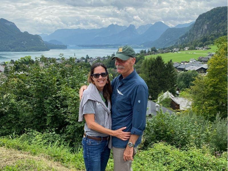 Senior couple standing in front of Sound of Music scenery with alpine mountains and a lake in the background