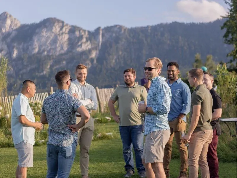 Group of friends on a European trip laughing and talking with mountains in the background