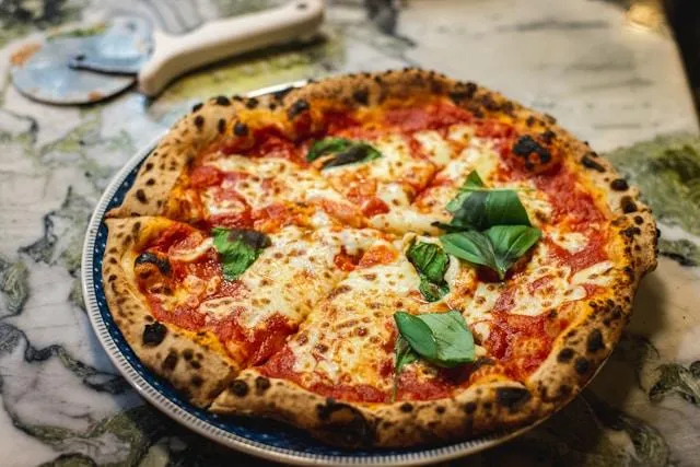 Freshly baked Italian pizza with cheese, tomato sauce, and basil, just out of the oven in Italy