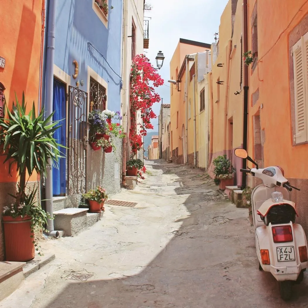 Colorful houses and a parked Vespa on a quiet, picturesque European alleyway