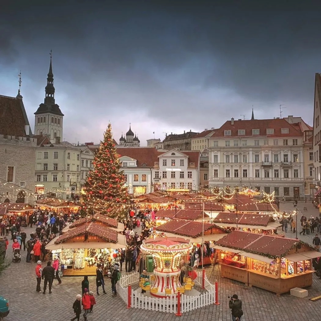 Charming European Christmas market with wooden stalls, twinkling lights, and a tall Christmas tree in a city courtyard