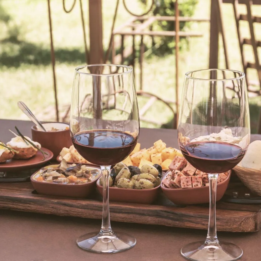 Two glasses of red wine served alongside traditional local food on a rustic table