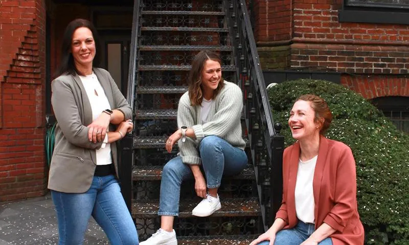 Three women on and in front of a staircase