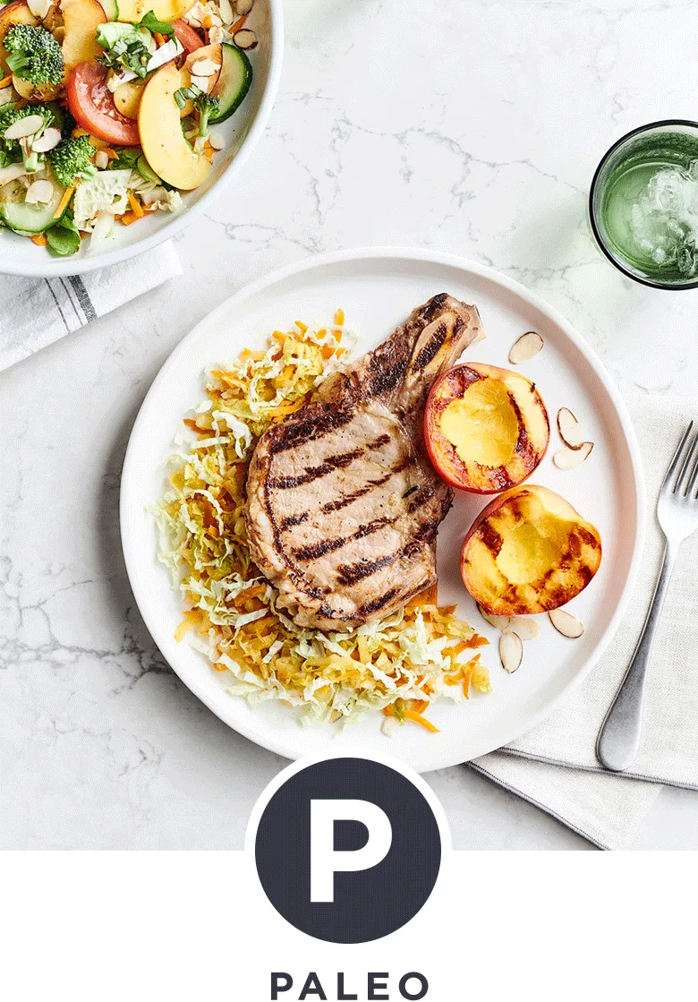 Juicy pork chop with sliced nectarines and a vegetable salad with shaved almonds