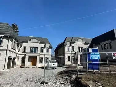 Large, two-story stone houses at a construction site with a "No Trespassing" sign; ideal for high-efficiency HVAC installation.