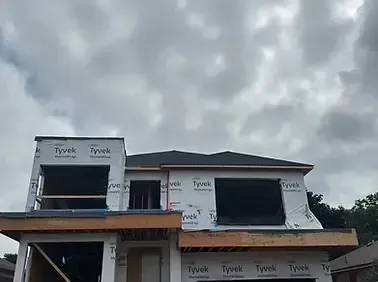 A two-story house under construction with Tyvek wrap, visible wooden framework, and a partially built roof under a cloudy sky in the greater toronto area gta